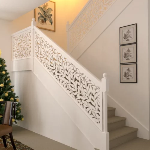 Staircase with leaf pattern railing and decorated Christmas tree.